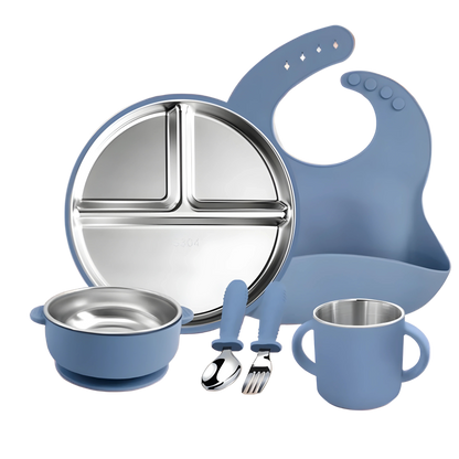 Children's dining set with blue bib, plate, bowl, cup, and utensils on a wooden surface.